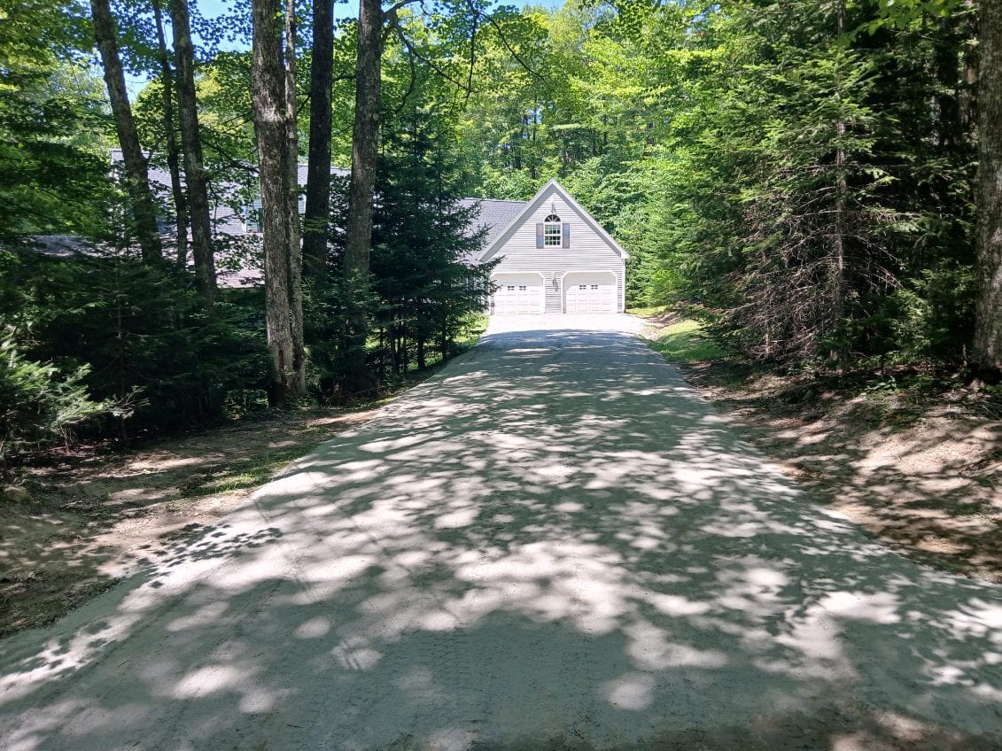 Fresh gravel driveway graded through the woods to the garage